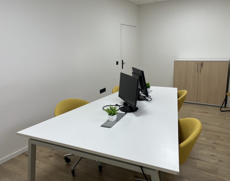 Bureau de coworking au rez-de-chaussée de La Coloc à Pau, équipé pour 5 postes avec table blanche et chaises jaunes.