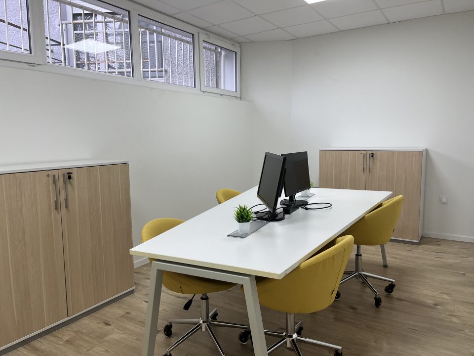 Bureau de coworking au rez-de-chaussée de La Coloc à Pau, équipé pour 5 postes avec table centrale et chaises jaunes.
